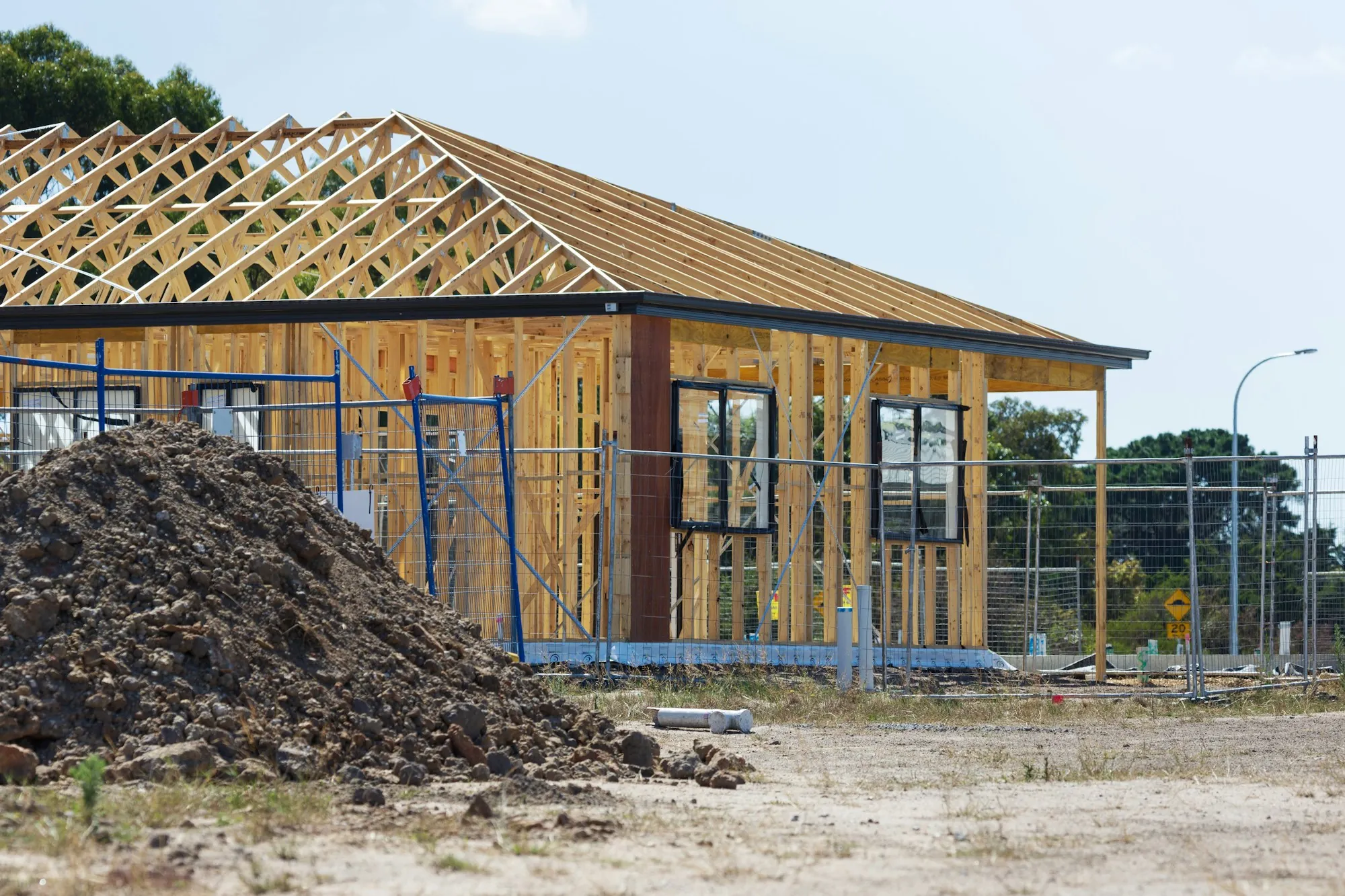 New single-story home framing beside a dirt pile