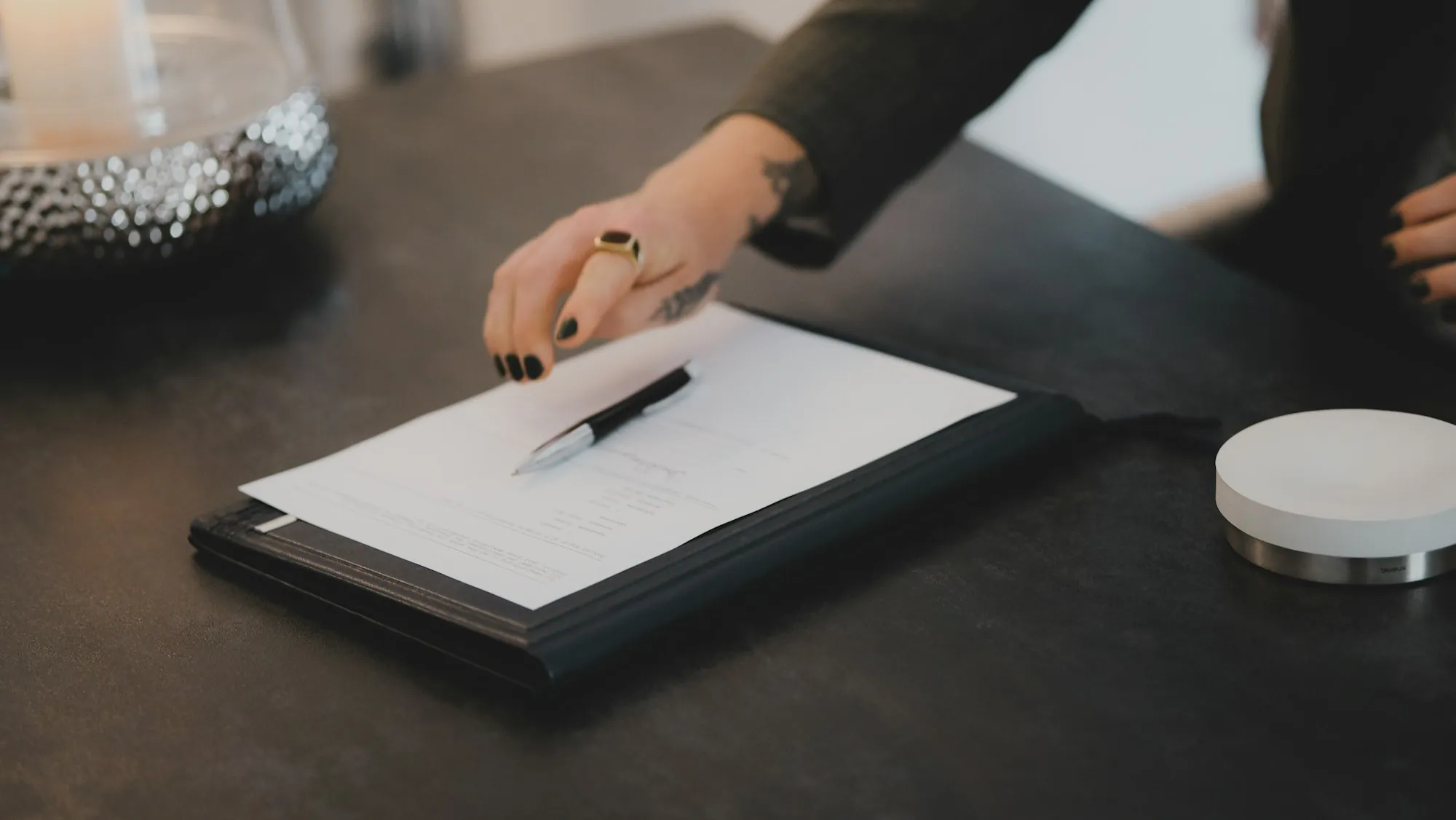 Hand with a pen over a document on a clipboard