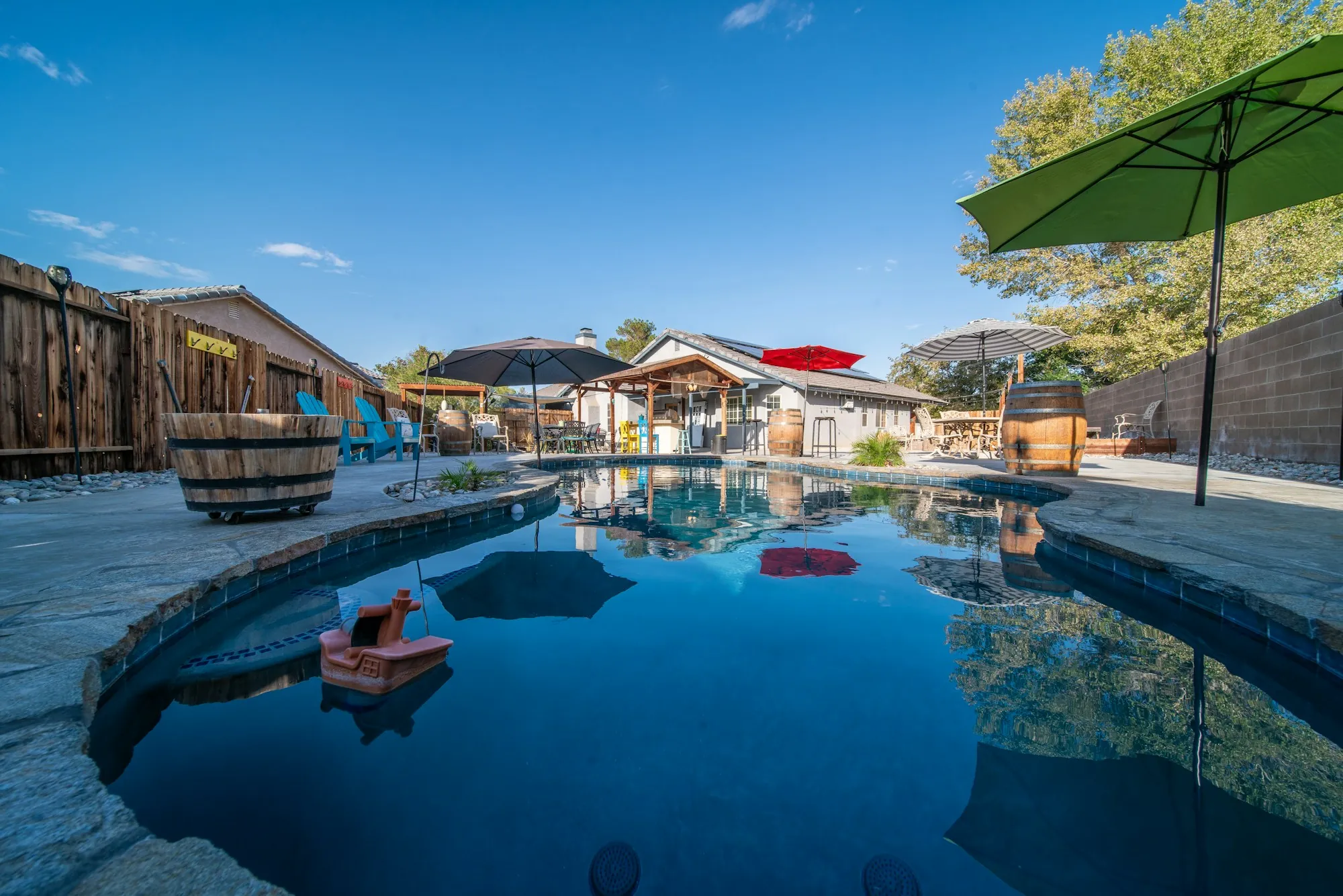Backyard swimming pool surrounded by a wood fence and patio